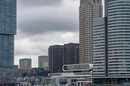 Multiple high-rise buildings and skyscrapers stand against a cloudy sky, showcasing modern architecture and urban construction in a densely built cityscape  in Rotterdam