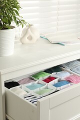 Chest of drawers with different folded clothes indoors, closeup