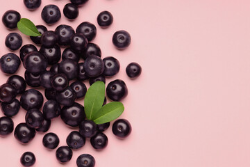 Ripe acai berries and leaves on pink background, flat lay. Space for text