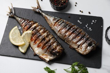 Delicious grilled mackerel, parsley, spices and lemon on white table, above view