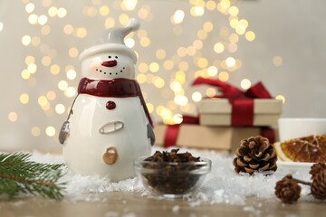 Funny snowman figure and other decor on table against blurred lights