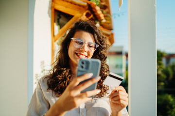 Young caucasian woman using credit card to buy online on her phone 