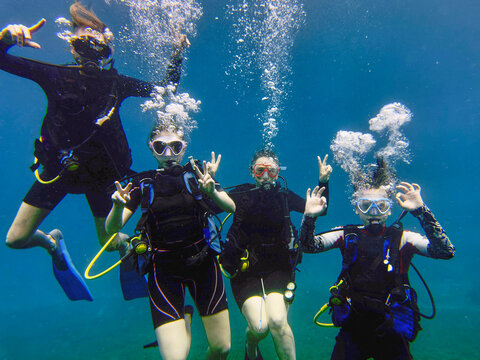 Portrait family scuba diving underwater in sea and gesturing peace sign, Kingstown
