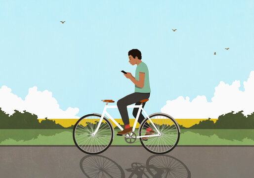 Man with smart phone texting and riding bicycle on sunny rural road
