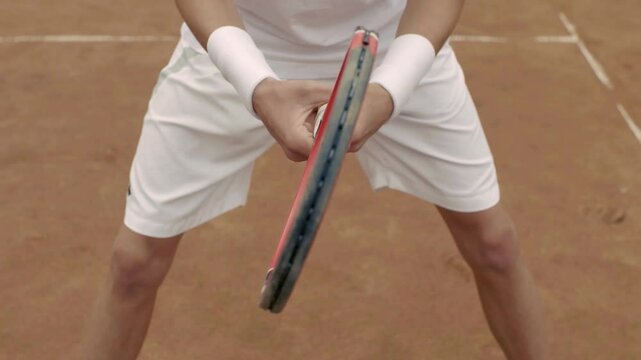 A focused and determined tennis player is getting ready for an impressive serve on the clay court