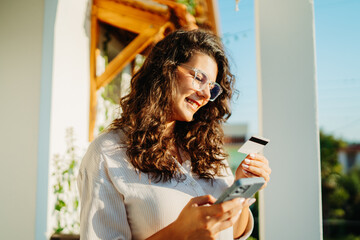 Young caucasian woman using credit card to buy online on her phone 