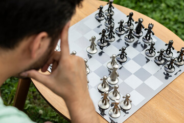 Thoughtful man playing chess outdoors	