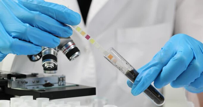 Scientist puts acidity indicator into soil in glass test tube. Laboratory assistant soil acidity examination in medical facility laboratory slow motion