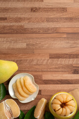 Fresh pomelo fruit with leaf on wooden table background.