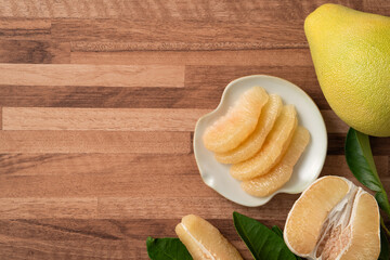 Fresh pomelo fruit with leaf on wooden table background.