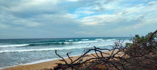 Small waves breaking on a sandy beach under a partly cloudy blue sky in Annaba Algeria