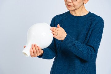 磁器の壺を鑑定するシニア女性 © metamorworks