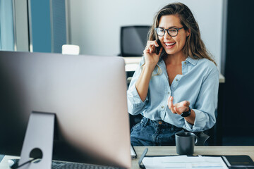 Business woman looking at her computer while talking with her clients on the phone