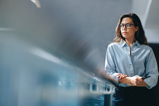 Thoughtful business woman standing on a balcony, reflecting on her goals and vision for her company