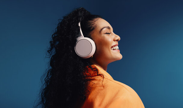 Woman enjoying music with headphones in vibrant colorblocking monochromatic set