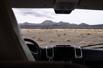 from inside vehicle view of volcano Cuervo and mount under cloudy sky in Tinajo, Lanzarote at...
