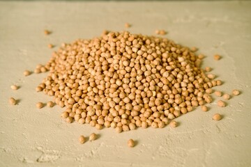 A pile of raw chickpeas placed on a light surface.