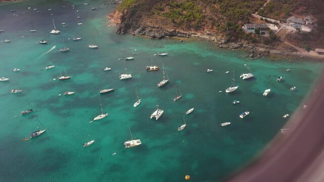 View from the plane window upon arrival in St Barth, in the Caribe, with the island and the boats moored in the crystal clear waters