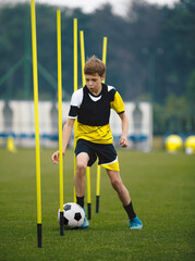 Soccer Players Running With Balls in Between Training Poles. Football Practice Session for Youth Sports Club © matimix