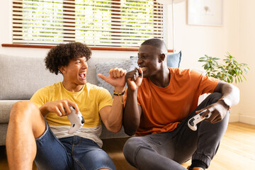At home, Playing video games, two diverse male friends laughing and enjoying time together indoors