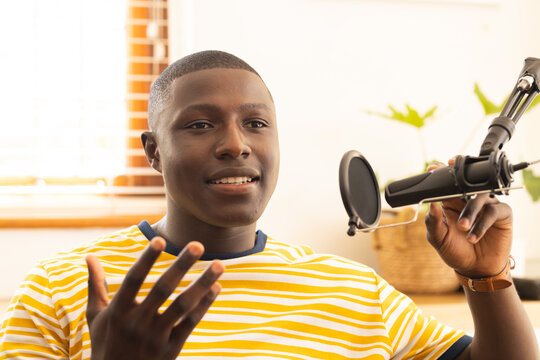 At home, Recording podcast, african american man speaking into microphone and gesturing with hand