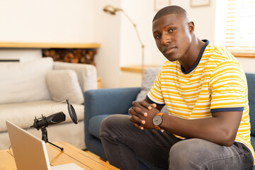 At home, Recording podcast, african american man sitting on couch with microphone and laptop