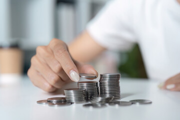 Close-Up of Hand Stacking Coins on a White Table - Financial Planning and Savings Concept