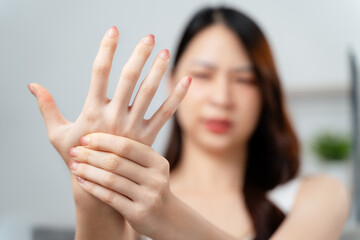 Closeup young woman sitting on sofa holds her wrist. hand injury, feeling pain. Health care.