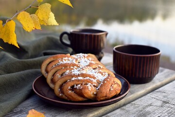 Swedish Cinnamon roll and coffee on a wooden table in nature.  Autumn time.Swedish fika.
