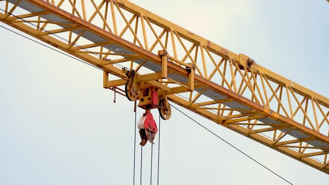 Work at height. Close up view of Tower crane at construction site. Heavy machinery and construction. Tall yellow metal structures used for lifting and moving