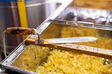 Electric knife for uncapping honey frames on the table. Harvest of honey on apiary, professional tool for opening honey frames, dirty in beeswax