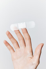 Hand holding adhesive bandage with white bandages on top and bottom