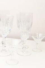 Vintage crystal glasses in front of beige background.