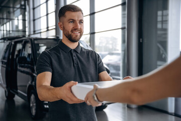 Hands, customer is bought the stuff. Woman is taking her order from delivery man, with the car