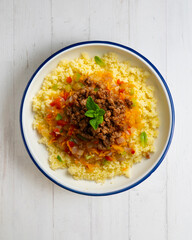 Couscous salad with vegetables and minced meat. Top view table with decoration.