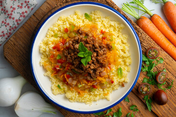 Couscous salad with vegetables and minced meat. Top view table with decoration.