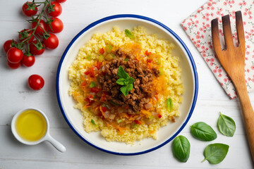 Couscous salad with vegetables and minced meat. Top view table with decoration.