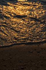 Waves lap the seashore and cover the small stones.