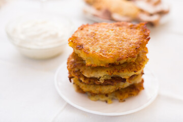 Potato pancakes with sour cream on white plate