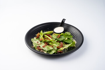 Fresh Green Salad with Dressing on a Black Plate