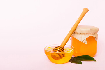 Honey in jar with leaves and honey dipper on colored background top view with copy text