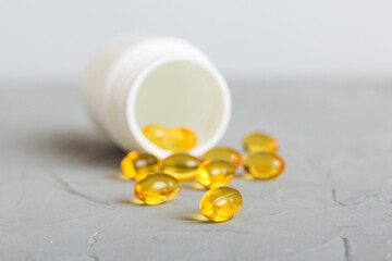 Soft gels pills with Omega-3 oil spilling out of pill bottle close-up. Gel capsules bottle white surface. Omega 3, multivitamins, Calcium, antibiotics. Health. Immunity