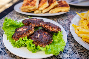 Round shaped balls of dry meatballs and french fries. Fried cutlet burger with lettuce on a plate