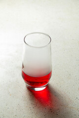 A glass of red liquid or red beer lies on a granite textured terrazzo tile table