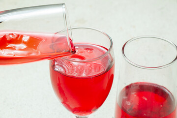 closeup of a glass of red liquid or syrup poured into a glass terrazzo granite table base background.