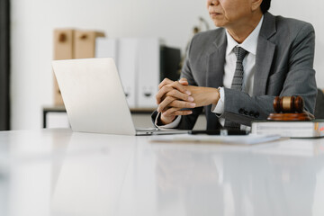 Lawyer Reviewing Case Files: A contemplative lawyer sits at his desk, reviewing case files on his laptop.  The gavel and legal documents subtly hint at the seriousness of his work.