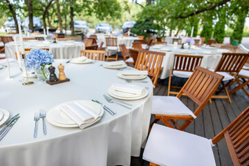 Beautifully organized event - round served table banquet ready for guests, round decorated table with empty plate, glasses, forks, napkin.