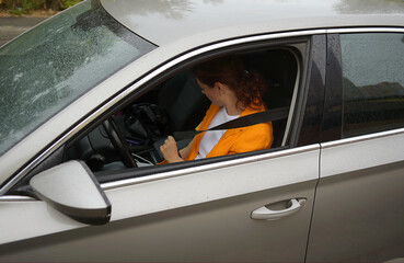 Naklejka premium Portrait of a girl driving a car in the city. traveling by automobile and enjoying road trip