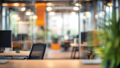 A blurry office interior. A desk with computer and chair is in the foreground. Plants and other office spaces are visible in the background