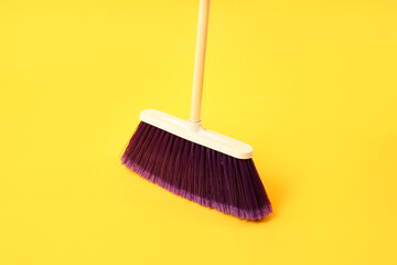 One bright cleaning broom on yellow background